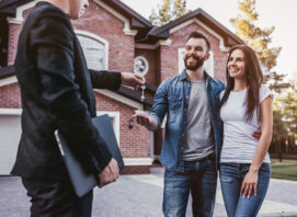 A couple getting keys to their new home from their real estate agent.