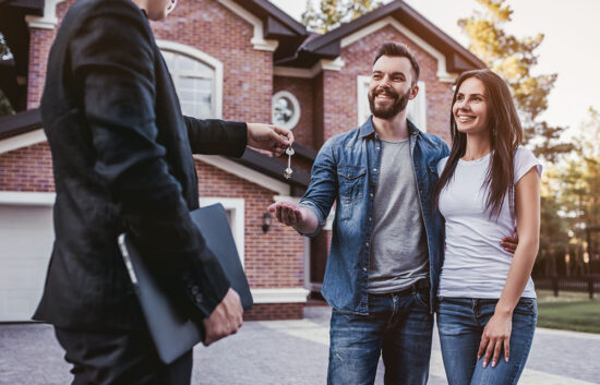 A couple getting keys to their new home from their real estate agent.